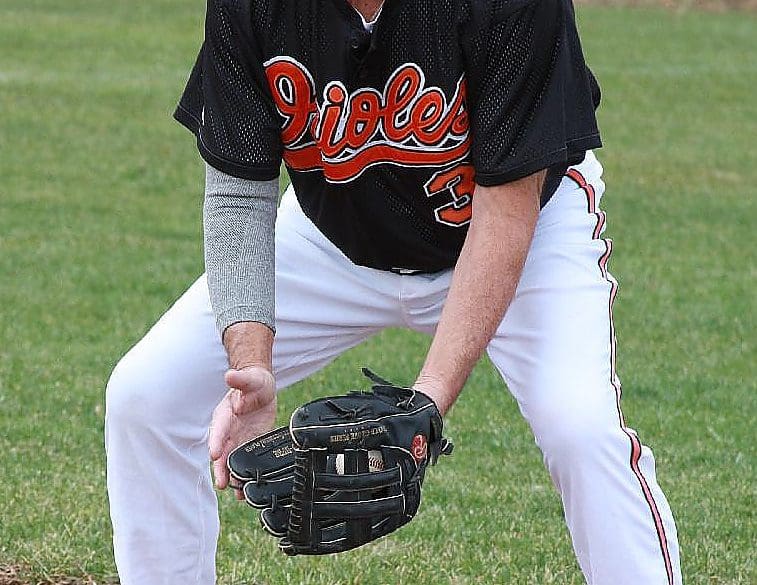 A baseball player is holding his glove in the outfield.