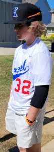 A man in white baseball uniform standing on grass.