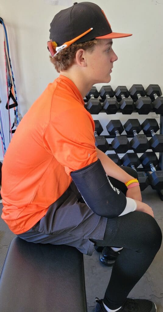 A man sitting in front of some weight plates.